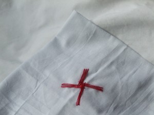 the folded corner of a white handkerchief, with an embroidered red cross in the 'Brigid's Cross' style